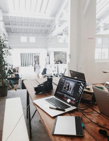 pexels-photo-699459-699459-1 A bright, modern workspace featuring laptops, a camera, and a drawing tablet in an indoor office.